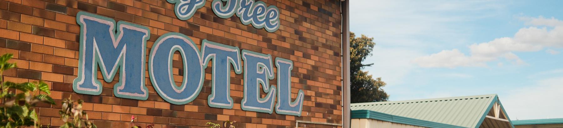 Red brick building with the text 'Fig Tree Motel' on the side in blue. 