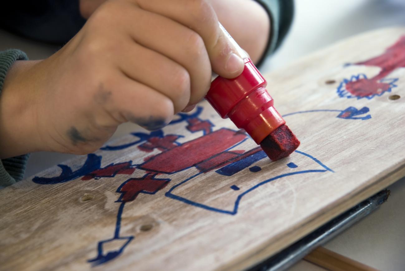 child drawing on a skateboard