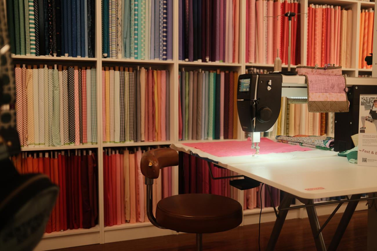 Interior of Sew Fab, Narrandera with a wall of fabric behind a sewing machine on table.